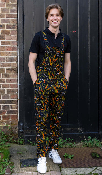 Model smiling and posing in Run & Fly's quirky unisex dungarees, designed with a colourful leaf and skull print. The ethical slow fashion brand focuses on unique, eco-friendly designs.