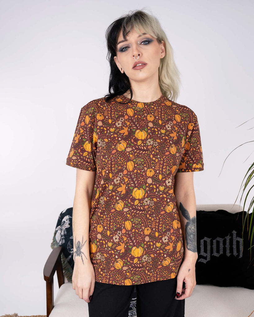 Front view of the Run & Fly Halloween: Autumn Pumpkins Short Sleeve T-Shirt worn by a model with edgy black and white hair. The warm autumnal tones and playful print of pumpkins and leaves stand out in a relaxed fit, perfect for spooky season.