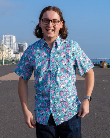 Front-facing shot of a smiling model in Run & Fly’s Spooky Stuff shirt. The teal fabric is adorned with pastel ghosts, crystals, and stitched hearts, celebrating slow fashion with a playful twist.